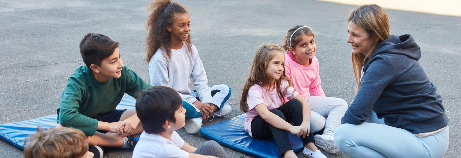 young children sitting on yoga mats listening to the instructor